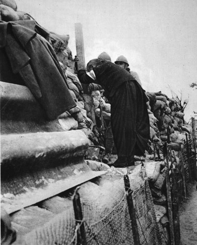 A French Priest in the lines: a Cure taking a peep through a trench-periscope, illustration from 